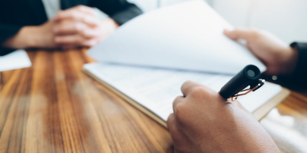 Closeup of a desk with hands looking over paperwork
